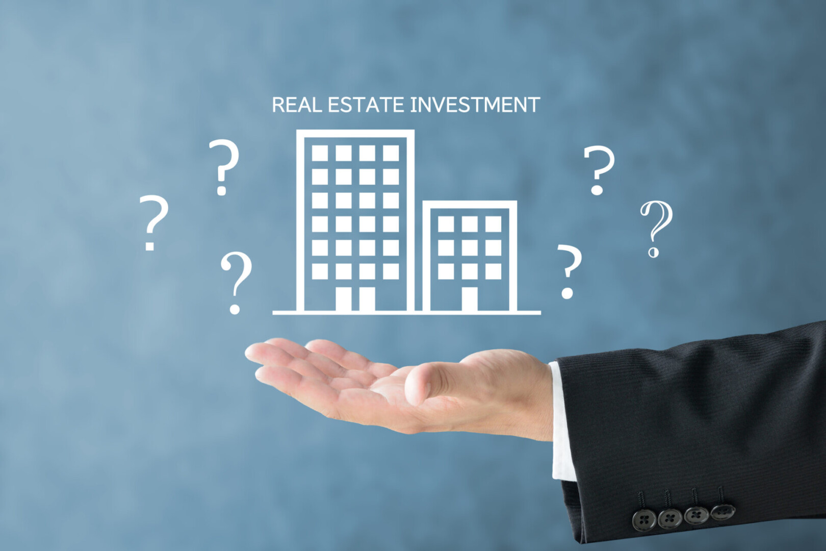 Business Man's Hand And Building Pictogram And Real Estate Investment Word With Question Marks